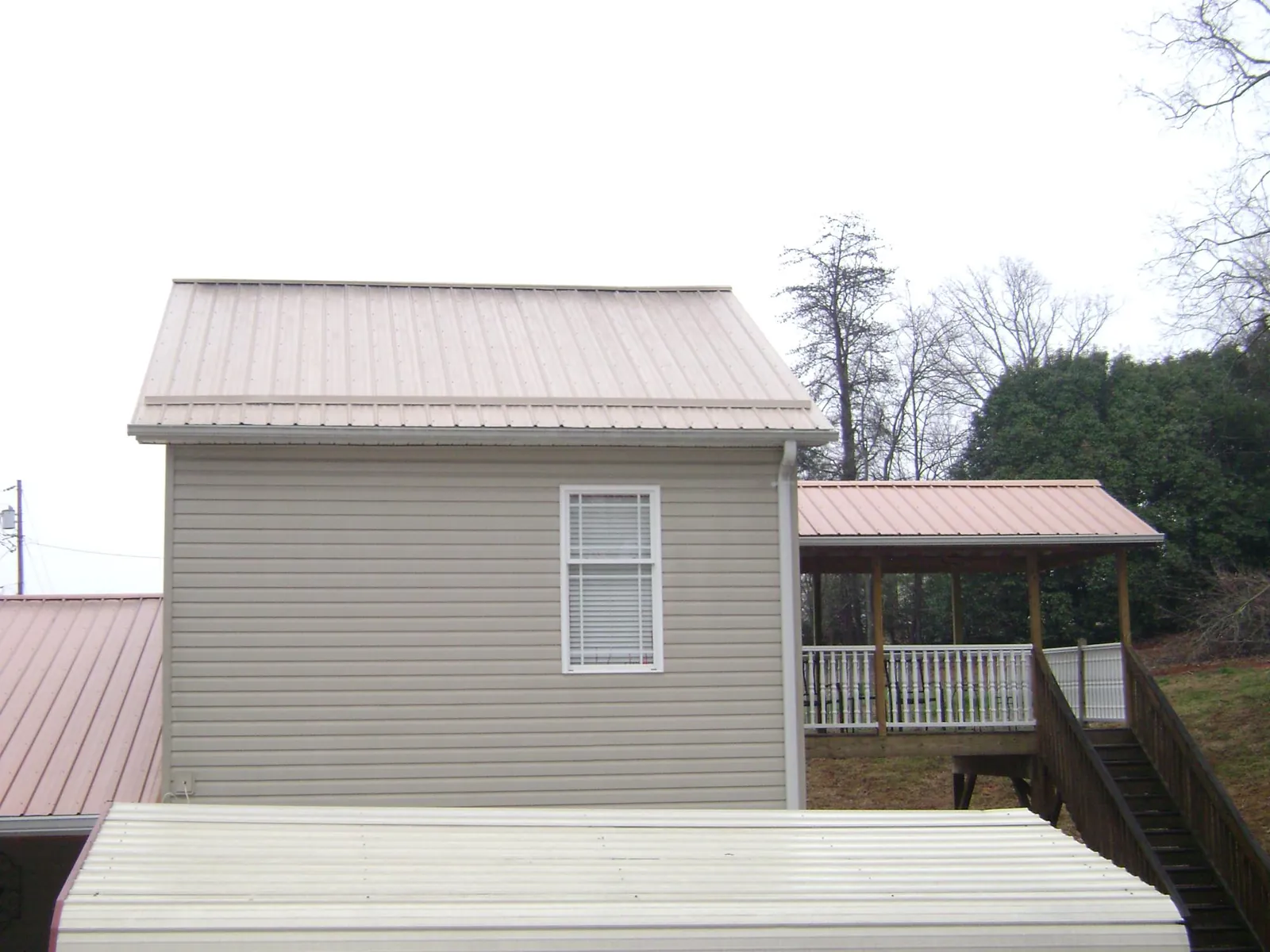 Tan metal roofs on a two story addition and attached porch, from a Roof Replacement job in Silver City
